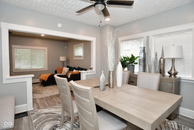 dining space featuring ceiling fan, wood-type flooring, and a textured ceiling