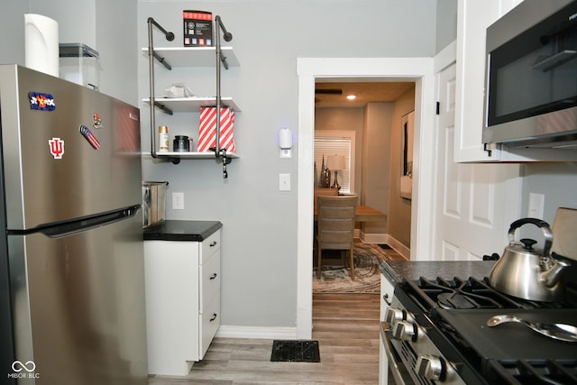 kitchen with white cabinets, appliances with stainless steel finishes, and light wood-type flooring