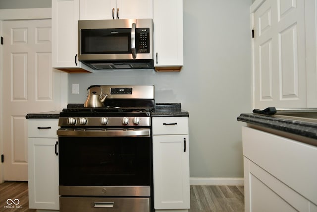 kitchen with white cabinets, appliances with stainless steel finishes, and hardwood / wood-style floors