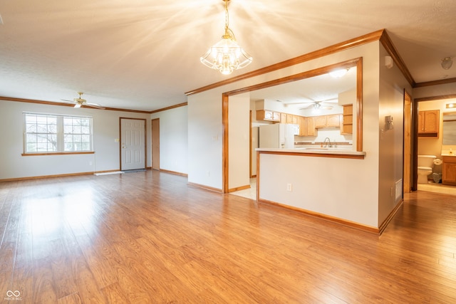 unfurnished living room featuring ceiling fan with notable chandelier, light wood-type flooring, and ornamental molding