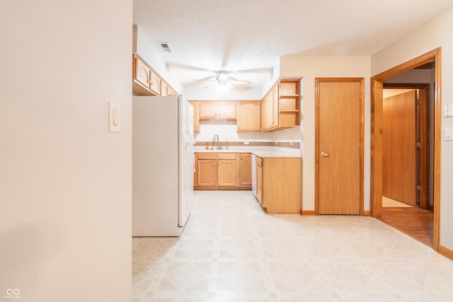 kitchen featuring light brown cabinets, white refrigerator with ice dispenser, sink, ceiling fan, and a textured ceiling