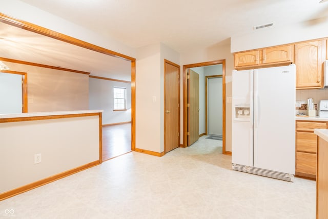 kitchen with light brown cabinetry, white appliances, and backsplash