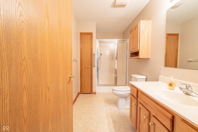 bathroom featuring vanity, toilet, and a shower with door