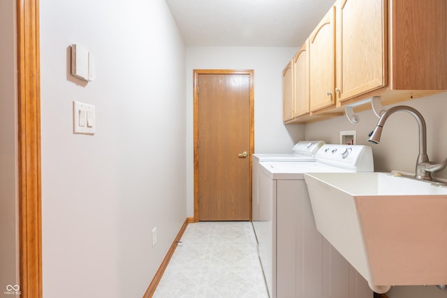 washroom featuring washing machine and dryer, sink, cabinets, and a textured ceiling