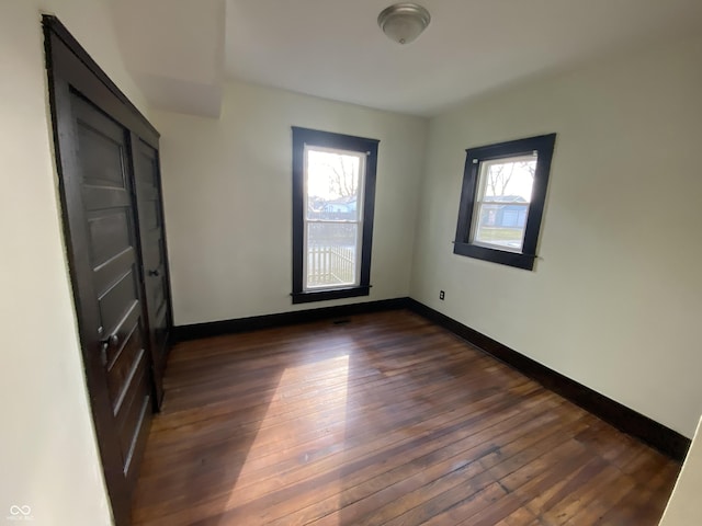 unfurnished room with a wealth of natural light and dark hardwood / wood-style floors