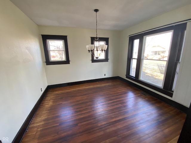 unfurnished dining area with dark hardwood / wood-style flooring and a chandelier