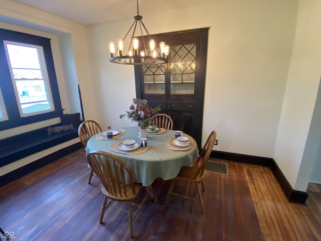 dining area with dark wood-type flooring and a notable chandelier