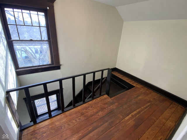 stairs featuring wood-type flooring and vaulted ceiling