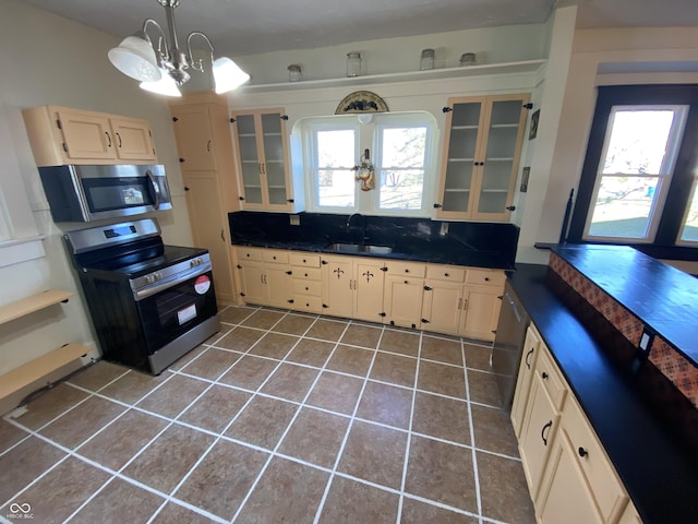 kitchen with sink, an inviting chandelier, tile patterned flooring, pendant lighting, and appliances with stainless steel finishes