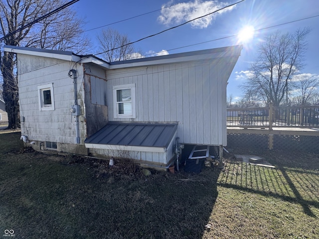 view of side of home with a wooden deck and a lawn