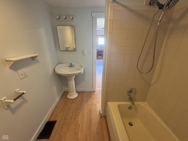 bathroom with hardwood / wood-style flooring and tiled shower / bath