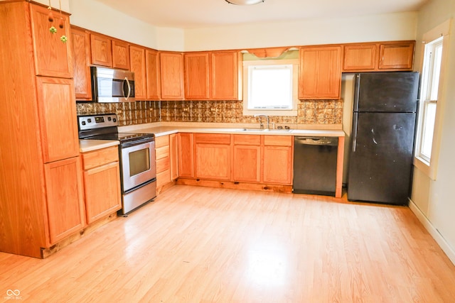 kitchen with tasteful backsplash, light wood-type flooring, and black appliances