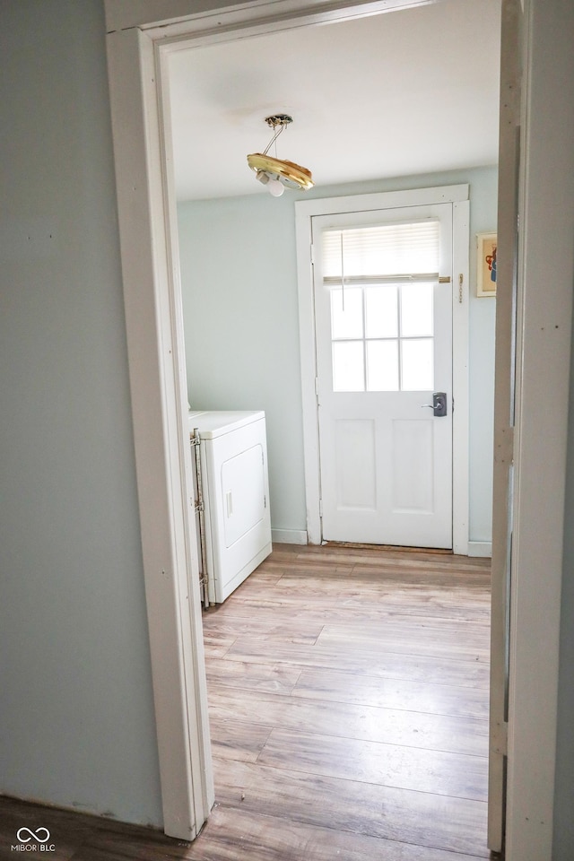 clothes washing area featuring washer / clothes dryer and light wood-type flooring