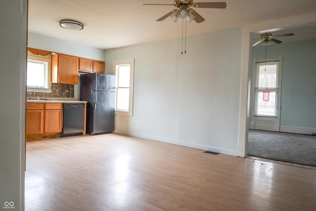 kitchen with tasteful backsplash, sink, black appliances, and light hardwood / wood-style floors