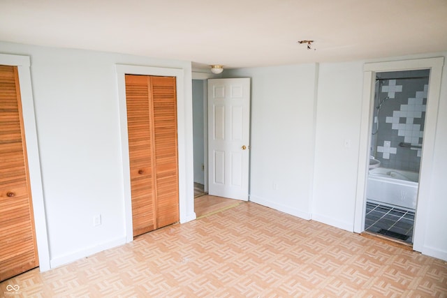 unfurnished bedroom with light parquet floors, two closets, and connected bathroom