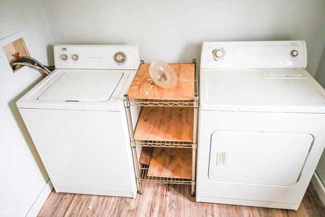 clothes washing area with separate washer and dryer and light hardwood / wood-style floors