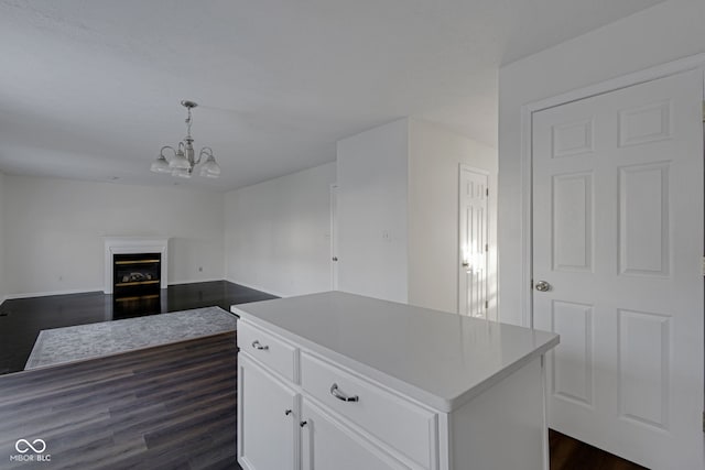 kitchen with white cabinetry, dark wood-type flooring, a notable chandelier, decorative light fixtures, and a kitchen island