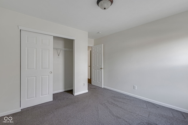 unfurnished bedroom with a closet and dark colored carpet