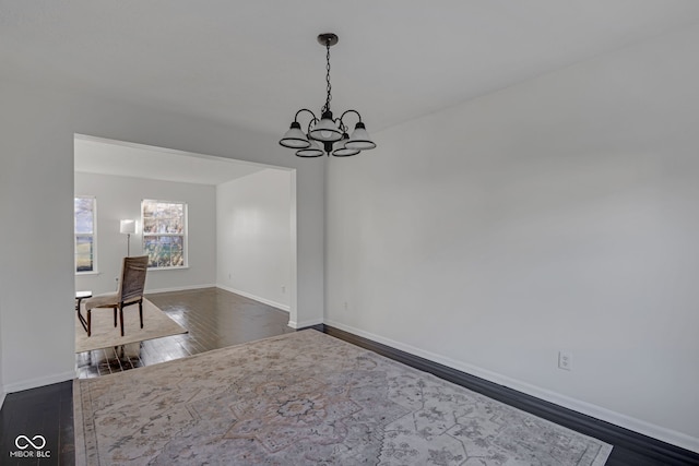 unfurnished dining area with dark hardwood / wood-style flooring and a notable chandelier