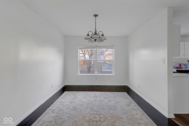 unfurnished dining area featuring dark hardwood / wood-style flooring and a notable chandelier