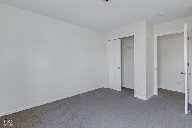 unfurnished bedroom with dark colored carpet and a closet