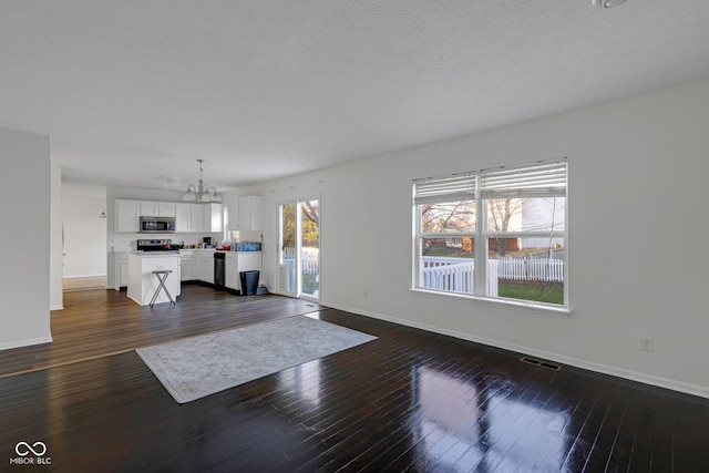 unfurnished living room featuring dark wood-type flooring and an inviting chandelier