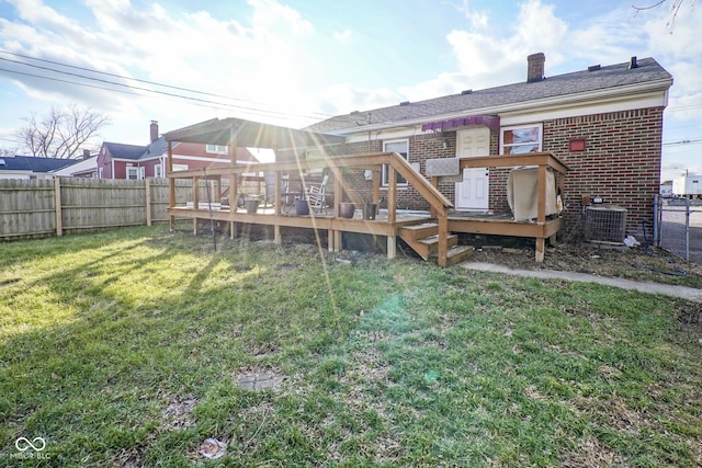 rear view of property featuring a lawn, central AC unit, and a deck