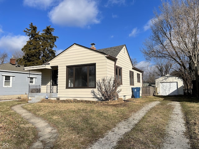 view of front of property featuring covered porch, a garage, an outdoor structure, and a front yard