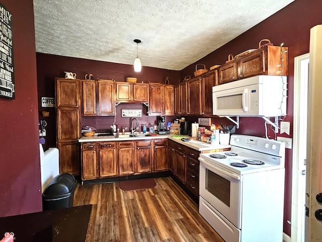 kitchen with dark wood-type flooring, white appliances, decorative light fixtures, and a textured ceiling