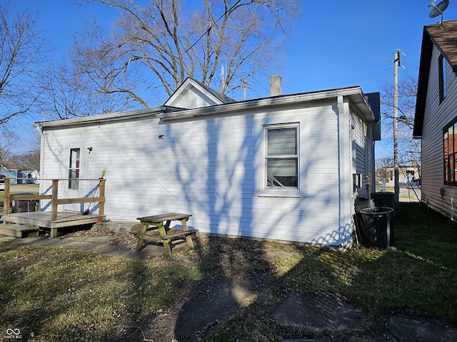 back of house featuring a lawn and a deck