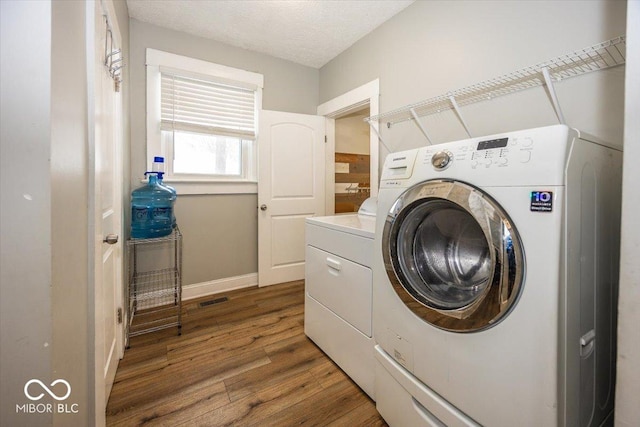 laundry room with hardwood / wood-style floors, a textured ceiling, and independent washer and dryer