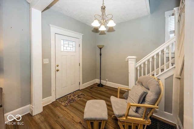 entrance foyer featuring a healthy amount of sunlight, a textured ceiling, an inviting chandelier, and dark wood-type flooring