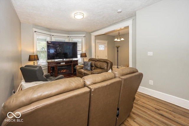 living room with a chandelier, a textured ceiling, and hardwood / wood-style flooring