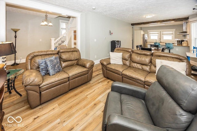 living room featuring light hardwood / wood-style flooring, a textured ceiling, and an inviting chandelier