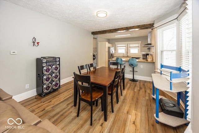 dining area with sink, light hardwood / wood-style floors, a textured ceiling, beam ceiling, and washer / dryer