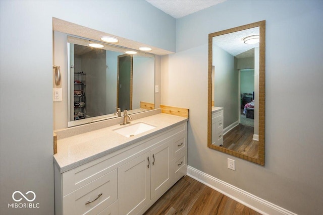 bathroom with hardwood / wood-style floors, vanity, and a textured ceiling