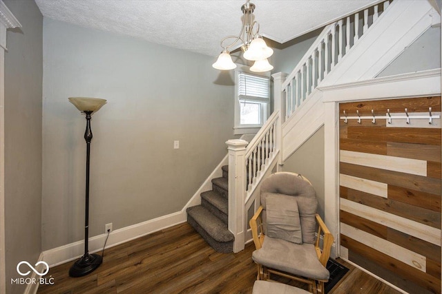 stairway with hardwood / wood-style floors, a textured ceiling, and an inviting chandelier