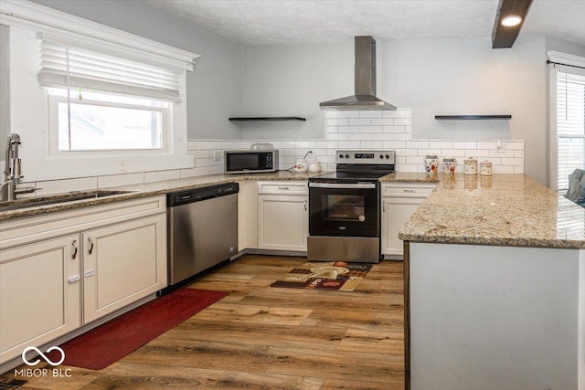 kitchen with sink, stainless steel appliances, wall chimney range hood, dark hardwood / wood-style flooring, and backsplash