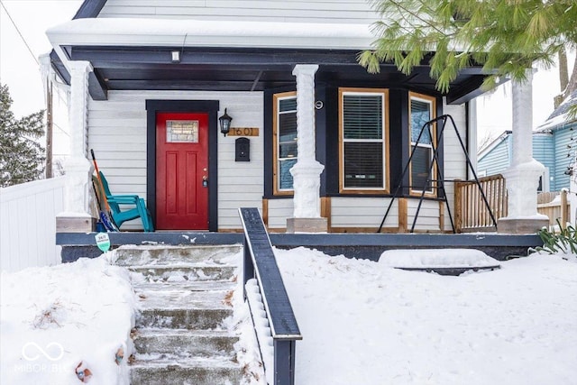 snow covered property entrance with a porch