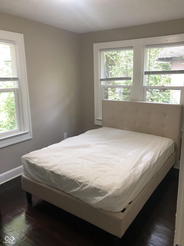 bedroom featuring multiple windows and dark hardwood / wood-style flooring