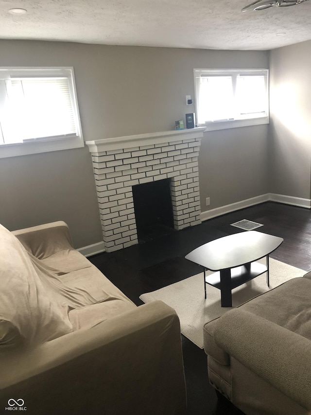 living room with dark wood-type flooring and a brick fireplace