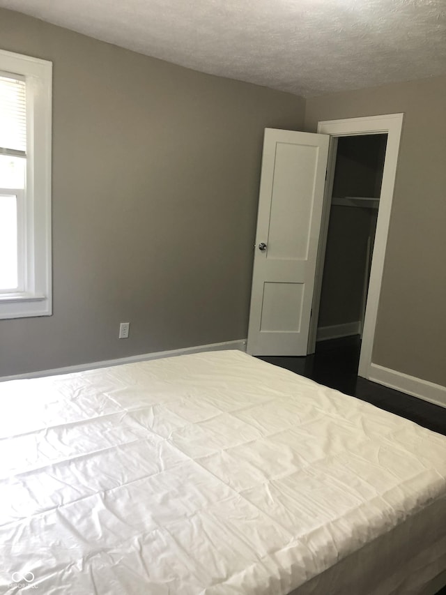 unfurnished bedroom with multiple windows, a closet, and a textured ceiling