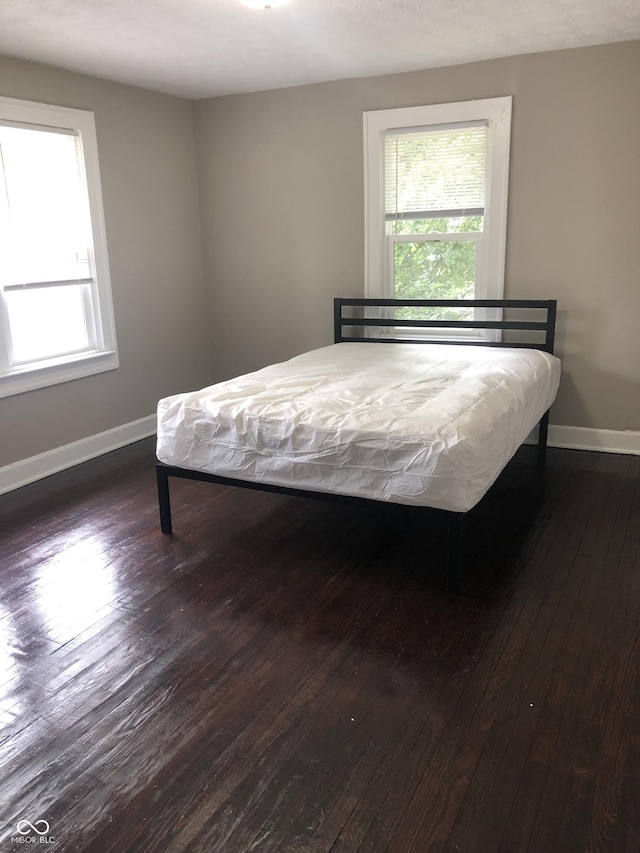 bedroom with dark hardwood / wood-style flooring and multiple windows