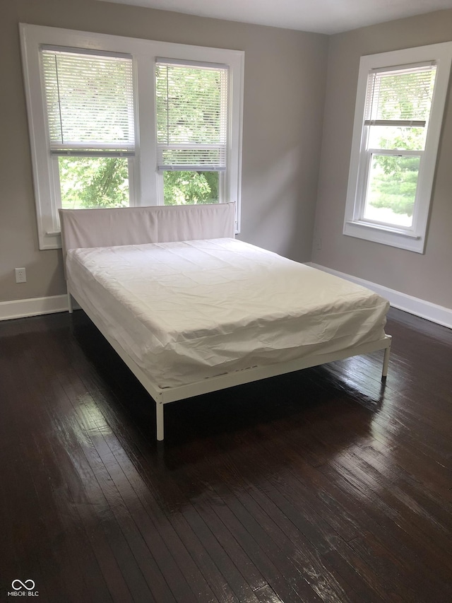 unfurnished bedroom with multiple windows and dark hardwood / wood-style floors