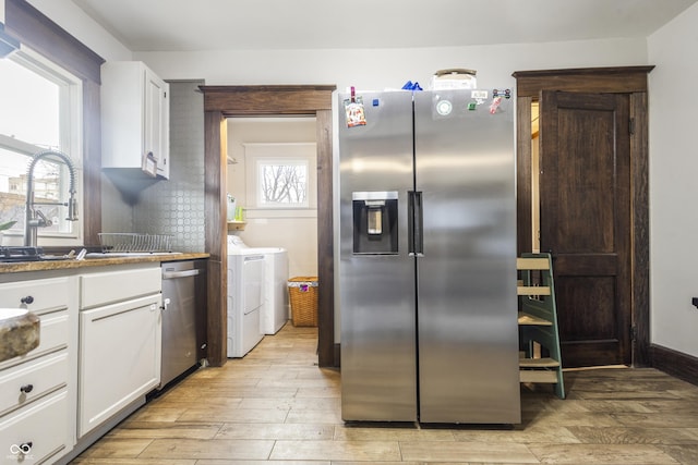 kitchen featuring white cabinets, sink, separate washer and dryer, light wood-type flooring, and stainless steel appliances