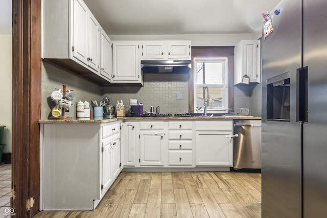 kitchen featuring backsplash, dark stone counters, white cabinets, light wood-type flooring, and stainless steel appliances