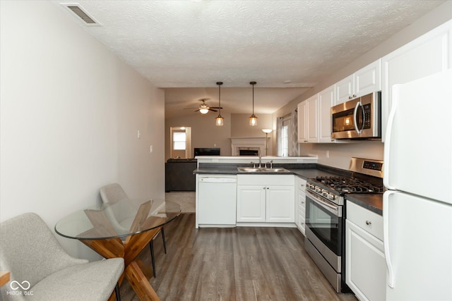 kitchen with white cabinetry, sink, hanging light fixtures, kitchen peninsula, and appliances with stainless steel finishes