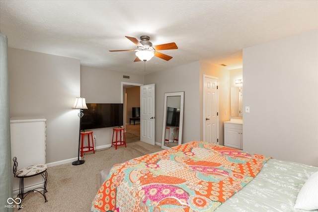 bedroom with ceiling fan, light colored carpet, and ensuite bath