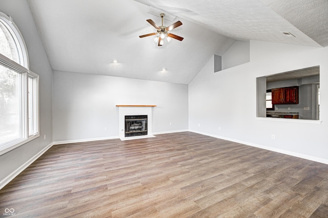 unfurnished living room with ceiling fan, light hardwood / wood-style floors, lofted ceiling, and a textured ceiling