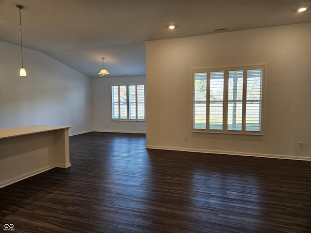 spare room with dark wood-type flooring and vaulted ceiling